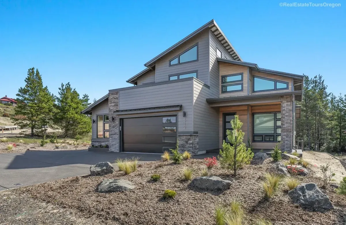Modern home exterior with garage, stone accents, wood trim, and xeriscaped landscaping at Duino Sea View Dr, Manzanita - Marnella Homes