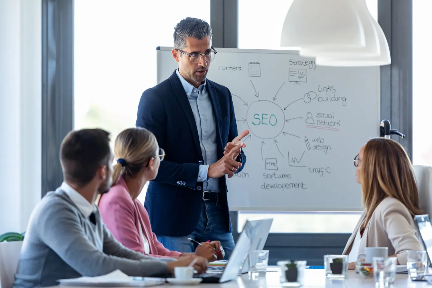 Blogs Packed With Expert Marketing Strategies for Home Builders 35 Business professional presenting SEO strategy diagram on whiteboard to team